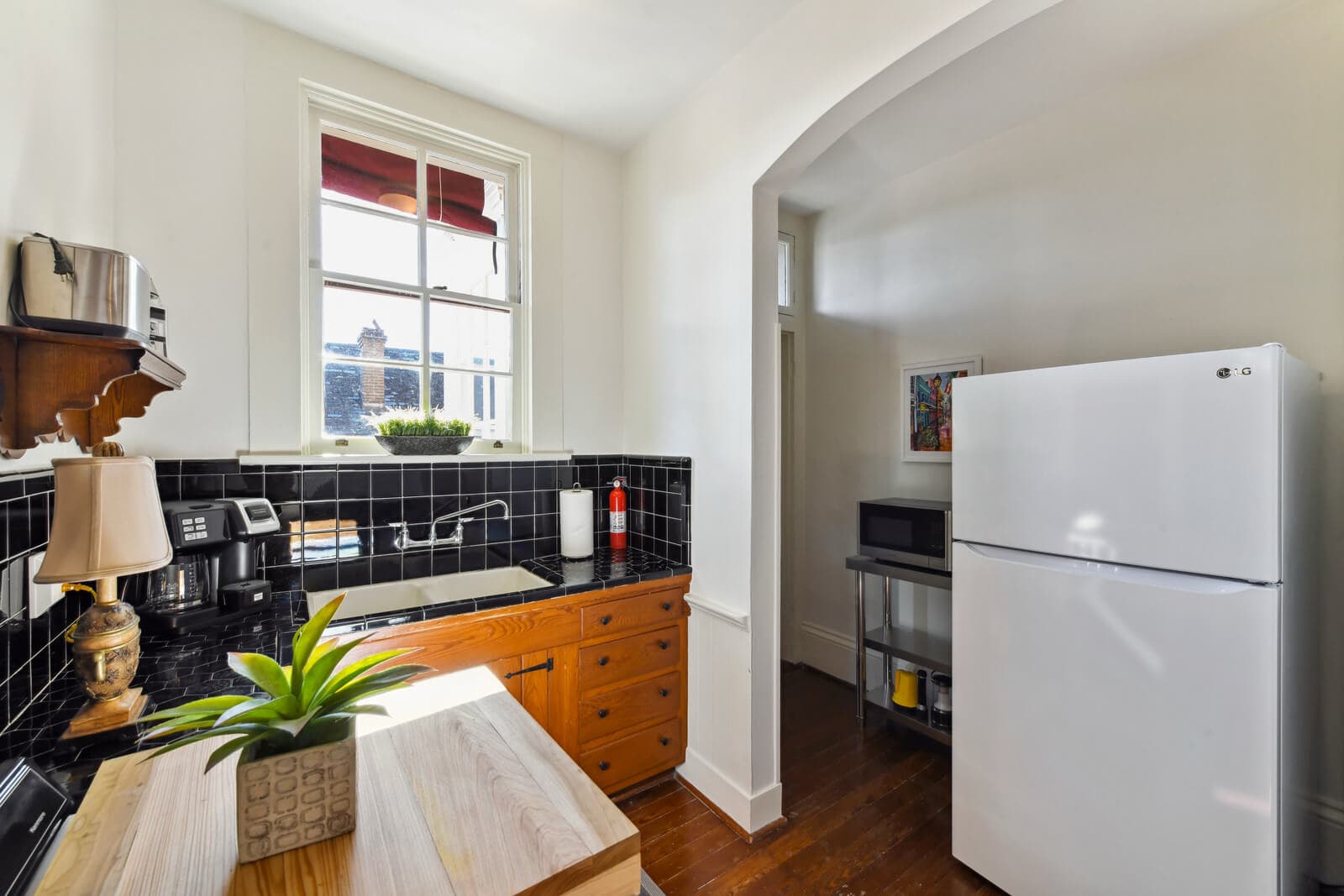 Bright kitchen with a black tiled backsplash, wooden cabinets, and a white refrigerator.