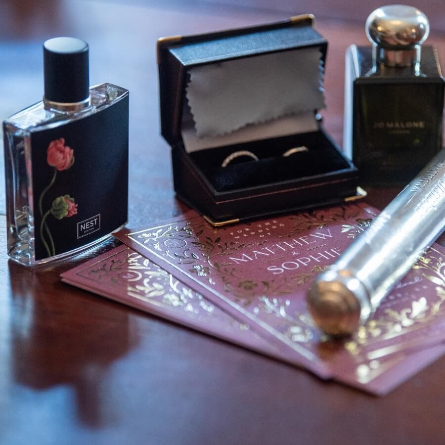 A collection of perfumes, a ring box, and decorative cards arranged on a wooden surface.