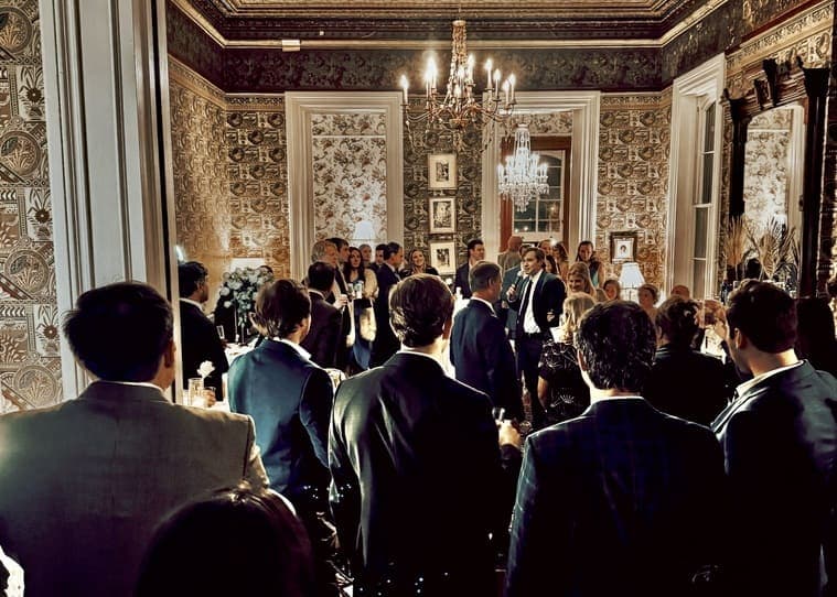 A group of elegantly dressed people gather in a beautifully decorated room for an event.