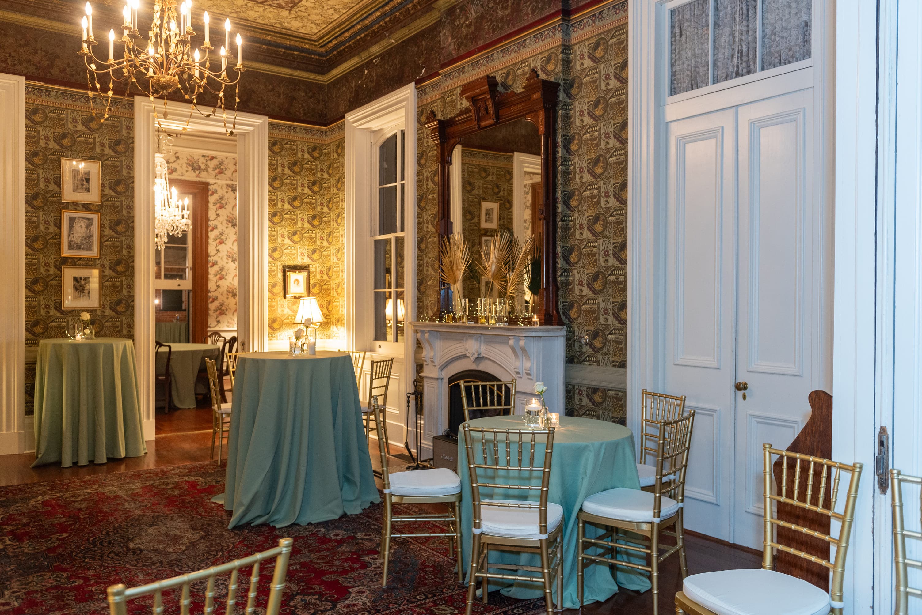 Elegant event space featuring tall ceilings, ornate wallpaper, and gold-accented furnishings.