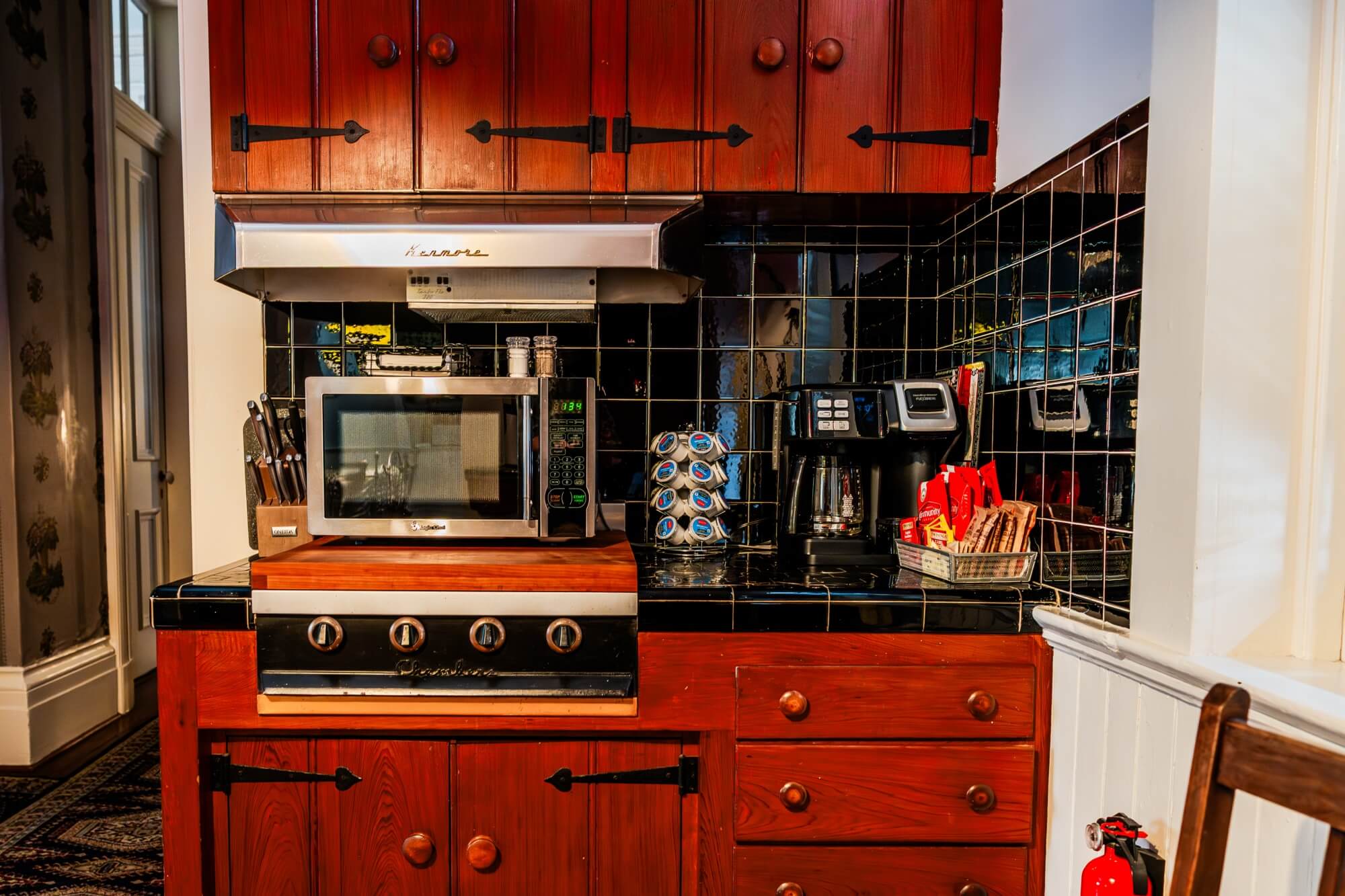 A modern kitchen featuring wooden cabinets, a microwave, an oven, and a coffee maker.