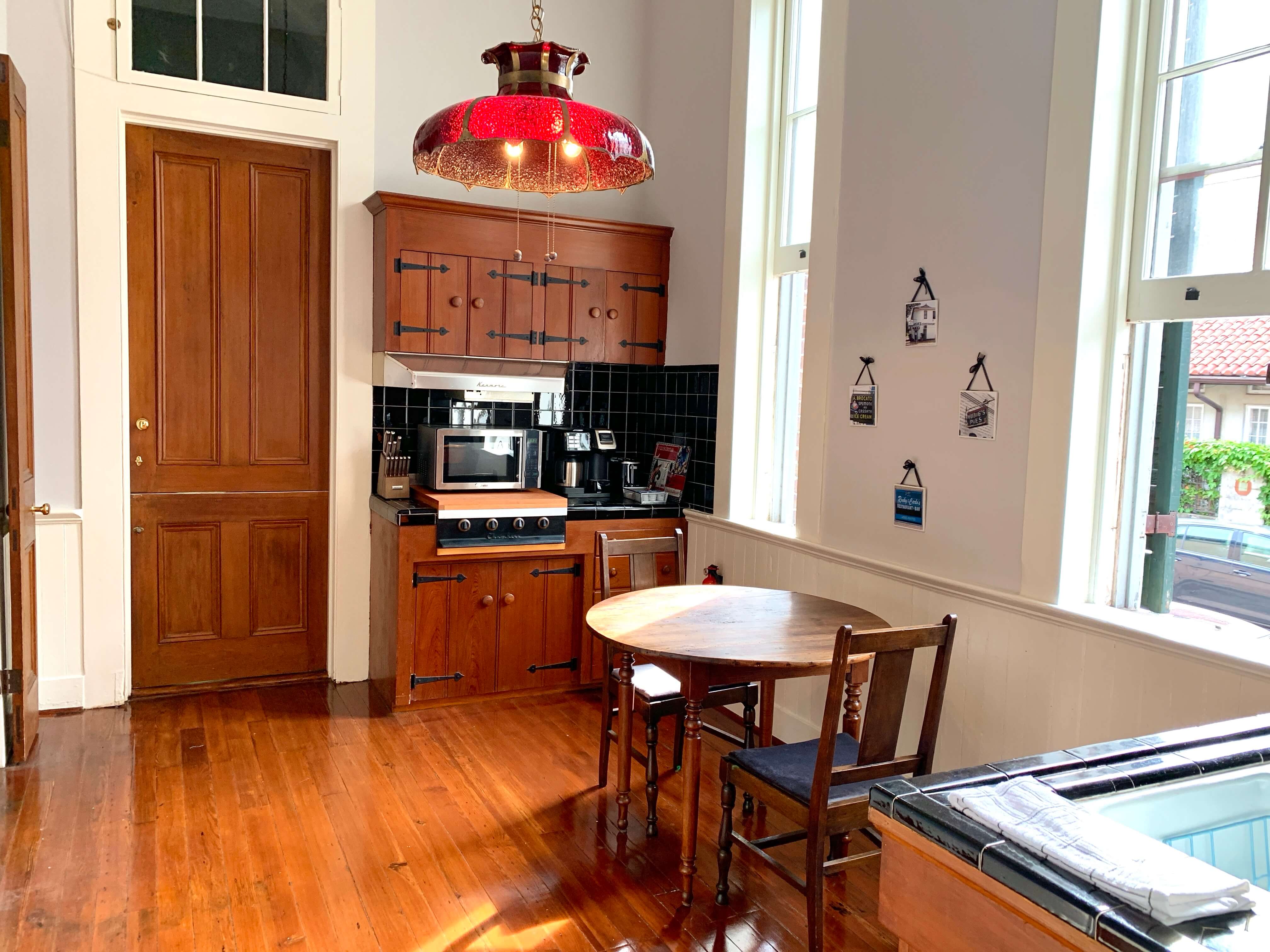 A cozy kitchen featuring wooden cabinetry, a round table with chairs, and a red pendant light.