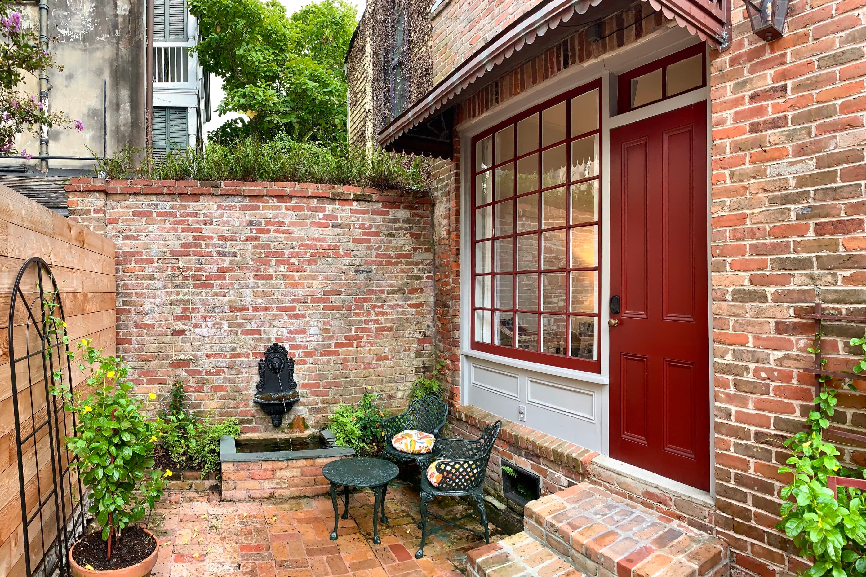 Cozy brick courtyard with a water feature, seating, and a red door.