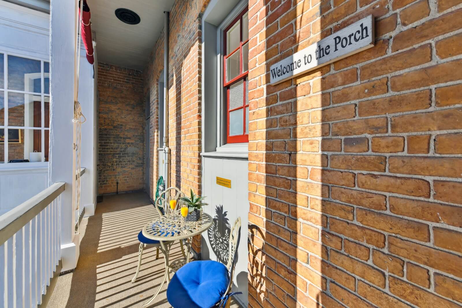 A cozy porch area featuring a small table and chairs, with a sign reading "Welcome to the Porch."