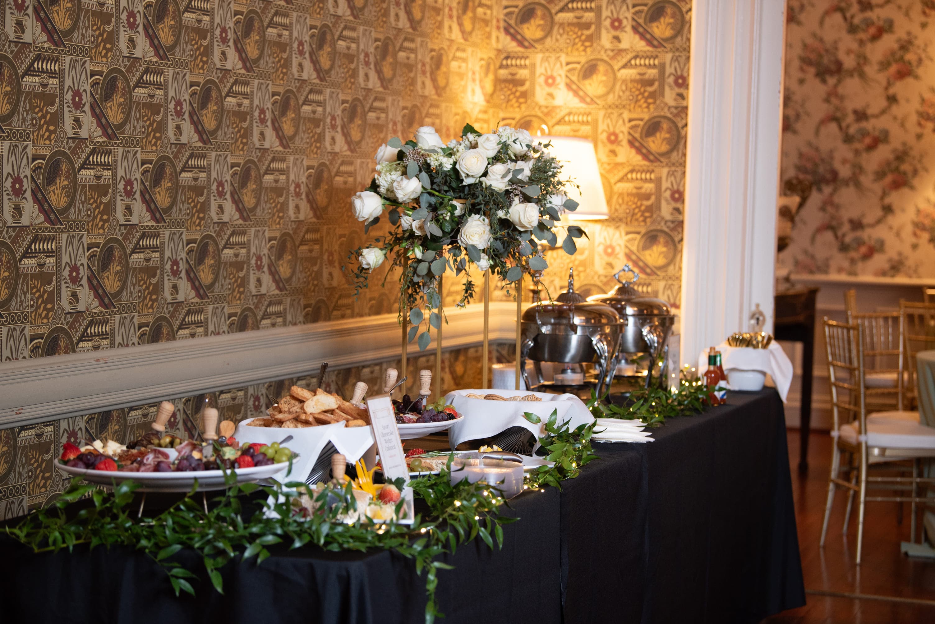 A elegantly arranged buffet table adorned with a floral centerpiece and various dishes in a decorated room.