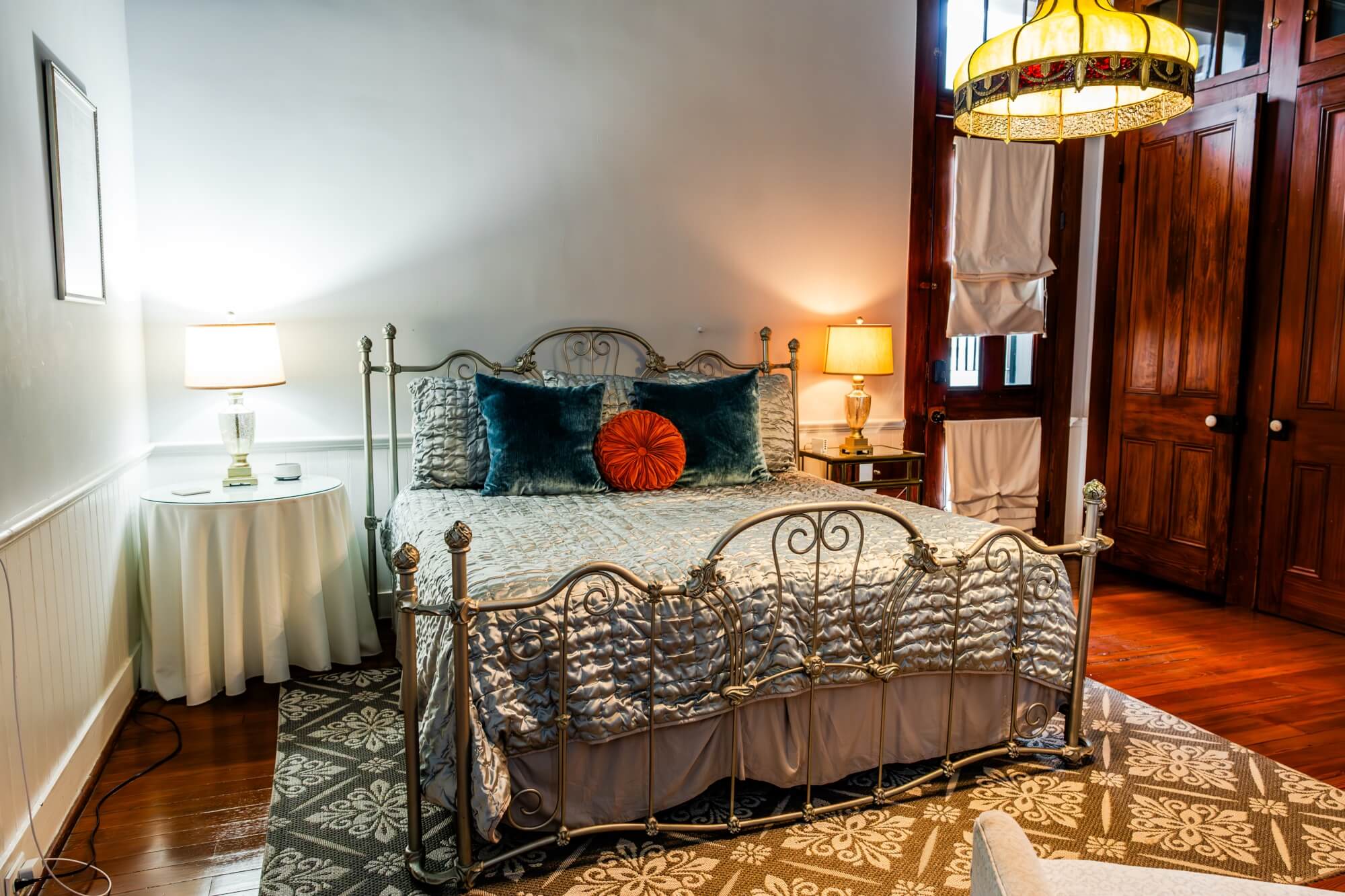 A cozy bedroom featuring a stylish metal bed, decorative pillows, and warm lighting.