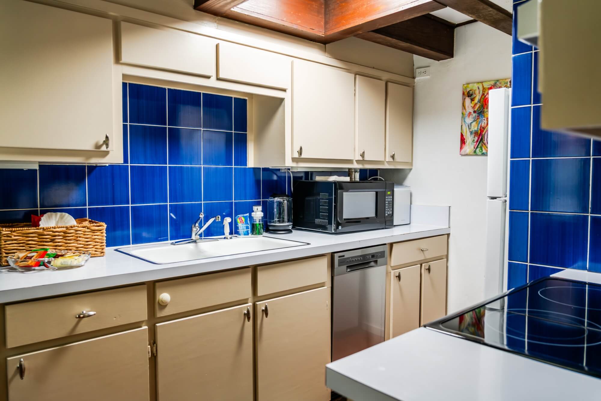 A modern kitchen featuring blue tiled walls, a white countertop, and various appliances.