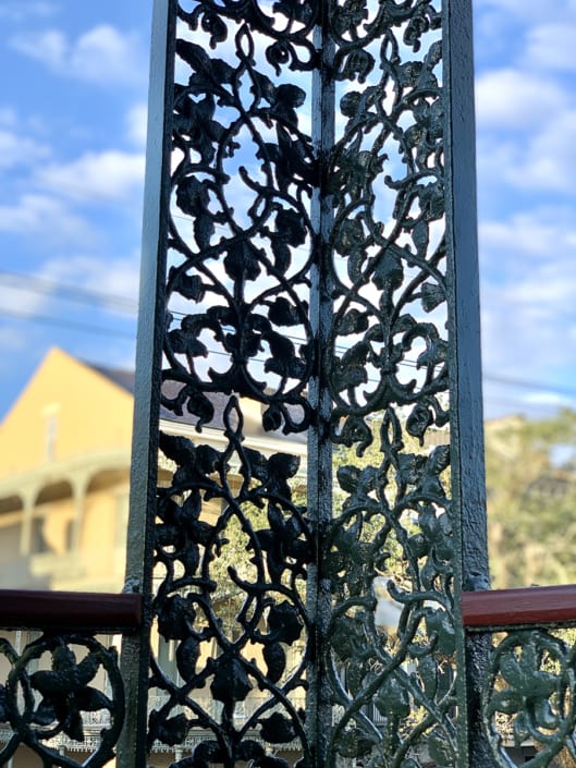 RUTHIEs Balcony ironwork closeup vertical w_ sky and yellow house
